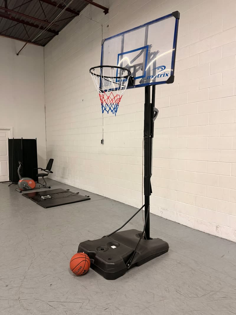 Recreation area with adjustable basketball hoop, exercise bike and floor mats